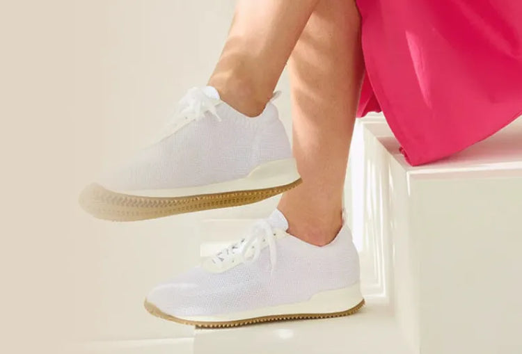 Eine Person sitzt auf einer Treppe und trägt weiße Schuhe neben einem Blatt. Text: Berufsschuhe für Krankenhaus, Praxis und Pflege.